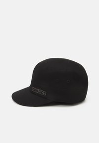 Cappello nero con visiera piatta, corona arrotondata e logo 'KANGOL' ricamato sulla parte frontale. Realizzato in un tessuto liscio e resistente.
