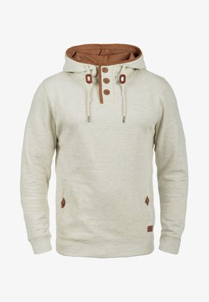 Bež kapuca s rjavimi poudarki, z kengurujskim žepom, tri gumbi in kapuco s vrvico. Mehka tekstura tkanine.