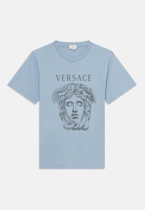 T-shirt bleu clair à manches courtes avec un grand motif tête de Méduse et le mot "VERSACE" imprimé en gris foncé au-dessus.