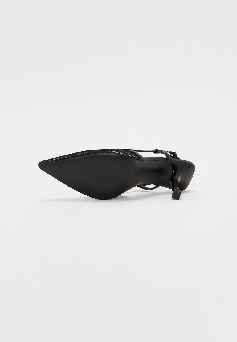 Pompe noire à bout pointu présentant un design épuré, en cuir verni brillant, et un talon fin avec des détails délicats de bride de cheville.