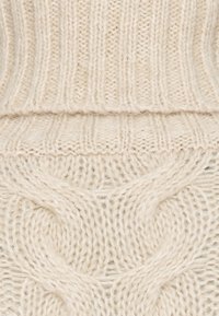 Gruby sweter z plecionego materiału w kolorze kremowym, z prążkowanymi i kablowymi wzorami, teksturowany, o miękkim wyglądzie, z szerokimi mankietami i dołem.