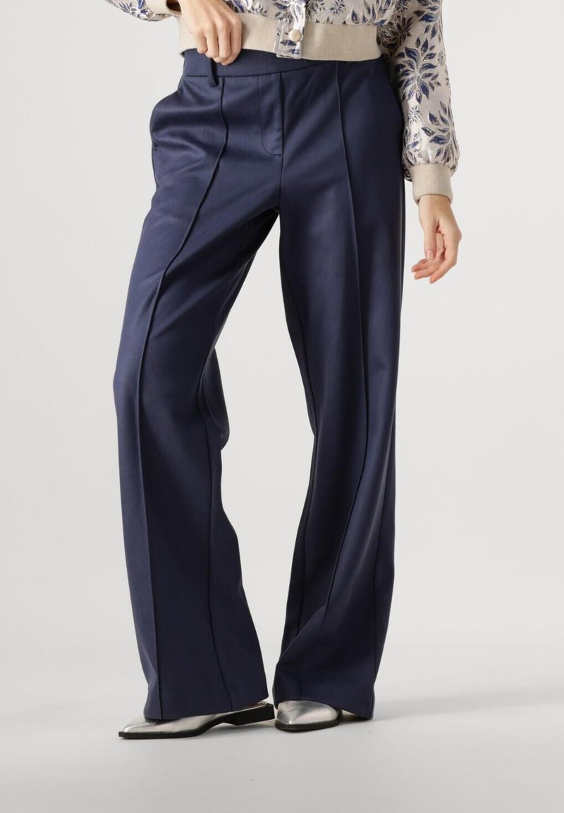 Navy brede broek in een gladde stof met voorplooien en verticale naaddetails, gecombineerd met zilveren schoeisel.