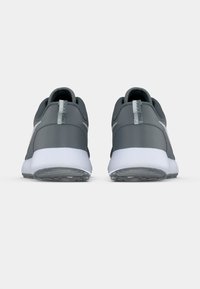 Ζευγάρι γκρι αθλητικά παπούτσια με λευκές σόλες, φωτογραφημένα από πίσω, εμφανίζοντας τις ταμπελίτσες της φτέρνας και τις υφασμένες εξωτερικές σόλες σε λευκό φόντο.