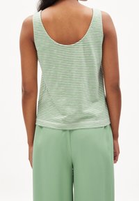 Top sans manches rayé en vert et blanc, avec un décolleté en scoop au dos ; porté avec un pantalon large vert assorti. Texture en coton lisse.