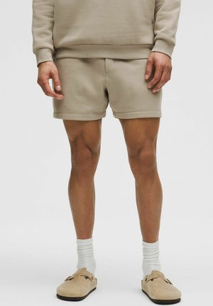 Beige Sweatshirt und passende Shorts aus weichem Stoff. Die Shorts sind enganliegend, mit einer glatten Textur und einem elastischen Bund.