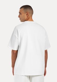 Hvid kortærmet t-shirt lavet af glat bomuld, med en afslappet pasform og rund halsudskæring. Ingen synlige mønstre eller detaljer.