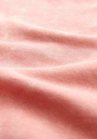 Textil moale roz cu o textură fină, având modele delicate de tricot și o drapare blândă, evidențiind calitatea sa ușoară și respirabilă.
