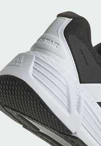 Mustat ja valkoiset urheilukengät, joissa on teksturoitua kangasta ja kumipohja. Ominaisuuksina on paksu muotoilu, korostetut urat ja brändäys kantapäässä.