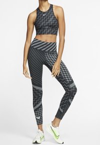 Czarny sportowy top crop i legginsy z geometrycznymi wzorami w odcieniach szarości i czerni. Zawiera pas i kieszeń na nodze.