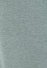 Tessuto di cotone azzurro chiaro, morbido, con una consistenza liscia e un leggero motivo mélange, caratterizzato da un design semplice senza segni o accenti visibili.