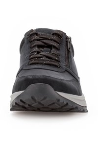 Schwarzer Sneaker, der eine Kombination aus Wildleder und glattem Material, eine strukturierte Sohle und einen seitlichen Reißverschluss mit verstärkten Nähten bietet.