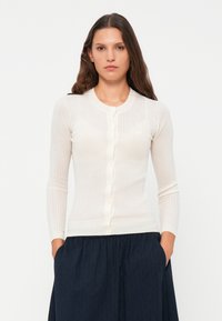 White ribbed cardigan with long sleeves and a round neckline, featuring front buttons and a fitted silhouette. Smooth texture.