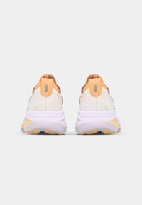 Sportliche Schuhe mit einem weißen und beigen Obermaterial, orangefarbenen Akzenten und einer strukturierten Oberfläche. Dicke, flexible Sohle mit einem Verlauf in Gelb.
