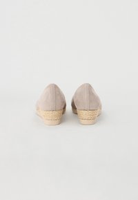 Beige suede espadrille shoes with a low, woven jute wedge heel and a smooth finish. Reinforced stitching along the back seam.