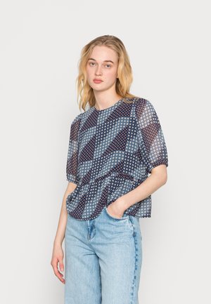 Blusa azul transparente com padrões florais, mangas curtas, decote redondo e cintura franzida. Combinada com jeans azul claro para um visual casual.