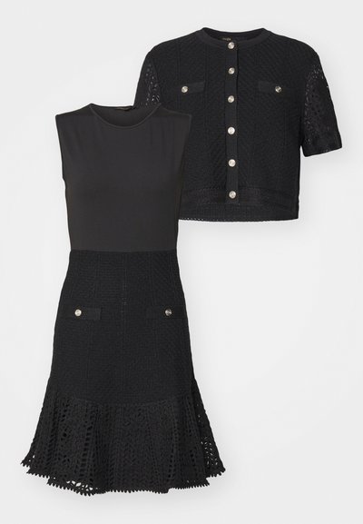 Černé šaty s přiléhavým tělem, rozšířeným krajkovým lemem a kapsami. Krátká černá bunda s tkanou texturou a kovovými knoflíkovými zapínáními.