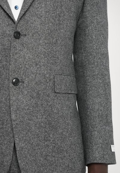 Grau gemusterter Wollblazer im Fischgrätenmuster mit drei Knöpfen, einer einzigen Brusttasche und kontrastierenden blauen Knopfdetails. Glatte Textur mit einem leichten Glanz.