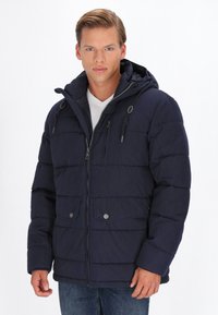 Jachetă puffer navy cu glugă, având închidere cu fermoar și nasturi, multiple buzunare și un design matlasat pentru izolare.