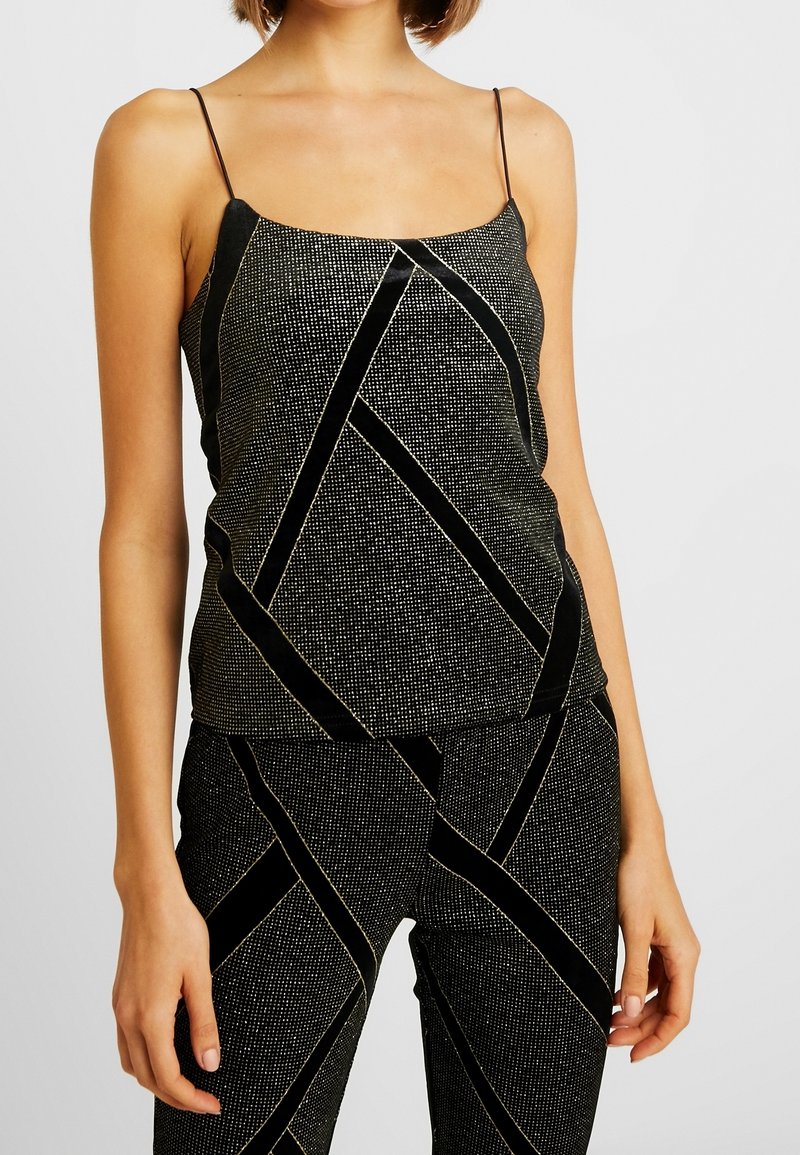 Svart ärmlös topp med tunna band, som har ett texturerat mönster av gyllene linjer och svarta sammetdetaljer i en geometrisk design.