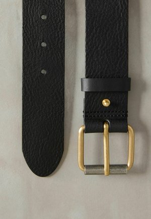 Must köie mustast nahast, tekstuurse viimistlusega, kuldse tooni pandla ja nahast kinnitusega. Mitmed augud suuruse reguleerimiseks on nähtavad.