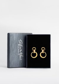 Goldene Ohrringe mit kreisförmigen Designs, strukturierten Ringen und funkelnden Akzenten, präsentiert in einer schwarzen Samtbox mit einem silbernen Logo.