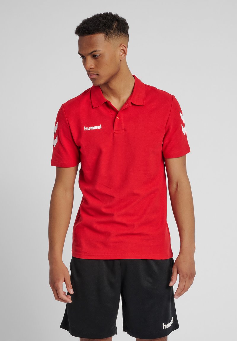 Rød polo skjorte med krave, korte ærmer og hvid "hummel" logo på venstre side. Sammen med sorte shorts med logo.