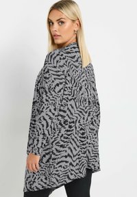 Kimono di colore grigio e nero con motivo, dal taglio ampio, maniche lunghe e un design fluido. Tessuto testurizzato con dettagli di stampa animale astratta.