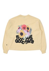 Gelbes Langarmshirt mit einem floralen Grafikdesign, das Sonnenblumen und Mohnblumen zeigt, kombiniert mit auffälligem schwarzen Text "FÜR DIE GUTEN ZEITEN".