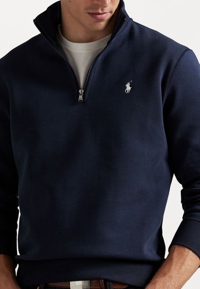 Marineblå zip-up sweatshirt lavet af bomuldsblanding, med et lille hvidt logo på brystet og ribbede manchetter.