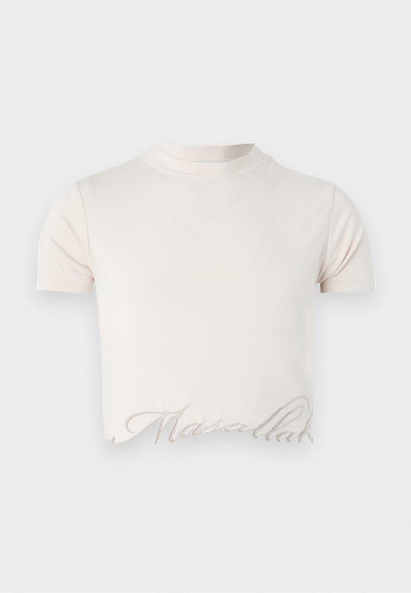 T-shirt court crop top couleur crème avec manches courtes et écriture brodée discrète le long du bord inférieur.