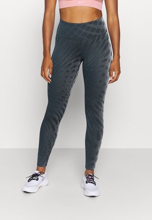 High-waisted, dark gray leggings with a textured stripe pattern. Paired with white sneakers featuring black laces and purple accents.