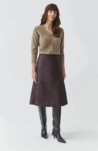 Brown knitted cardigan with buttons, paired with a dark brown A-line skirt, and knee-high black pointed-toe boots. Smooth textures throughout.
