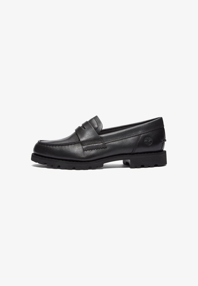 Mocassin noir en cuir à enfiler avec détails cousus, une bride décorative, une semelle robuste et un logo embossé au talon, présenté côté gauche.