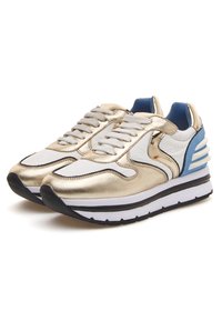 Sneakers oro e bianchi con una finitura metallizzata liscia, design stratificato, accenti blu e una suola nera spessa con intersuola bianca.