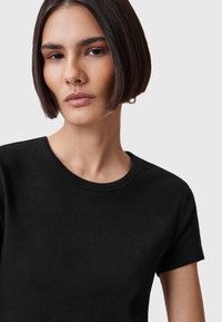 T-shirt nera a maniche corte realizzata in morbido tessuto di cotone, con un classico collo a giro e una superficie liscia e uniforme.