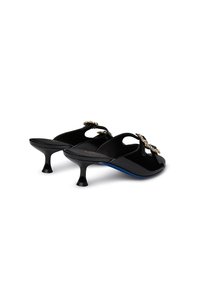 Black patent leather mules with a low, flared heel and a decorative jewel accent on the upper. Features open sides and a smooth texture.