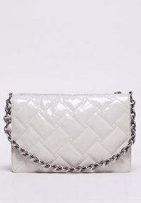 Valkoinen kiiltävä säkki, jossa on tikattu nahka, hopeinen ketjuolkapanta ja yläpuolelle suljettava vetoketju, tasaisella taustalla.