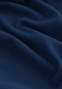 Tessuto blu navy con una texture morbida e una superficie liscia, che mostra una fine rigatura e pieghe delicate, indicando una qualità elasticizzata.