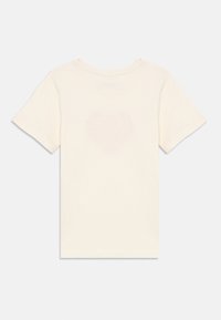 Μπεζ βαμβακερό t-shirt με κοντά μανίκια, που διαθέτει διακριτικό σχέδιο καρδιάς στην πλάτη. Κανονική γραμμή και απαλό ύφασμα.