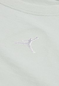 Svijetlozelena pamučna majica s bijelim izvezenim Jumpman logom. Tkanina ima glatku teksturu s finim rebrastim uzorkom.