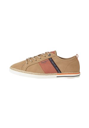 Zapatillas de lona beige con un acabado texturizado, que cuentan con una franja lateral roja, detalles en marrón y una suela blanca con un detalle trenzado y una franja negra.