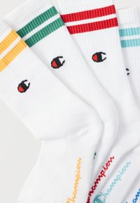 Κάλτσες από λευκό βαμβάκι με πολύχρωμες ριγέ λεπτομέρειες (κίτρινο, πράσινο, κόκκινο) στην κορυφή. Διαθέτουν λογότυπο και όνομα της μάρκας κεντημένα σε κάθε κάλτσα.