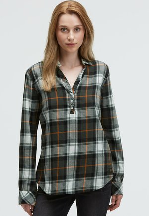 Plaid button-up shirt in black, white, and orange, featuring a collar, long sleeves, and a split hem. Made from a soft fabric.
