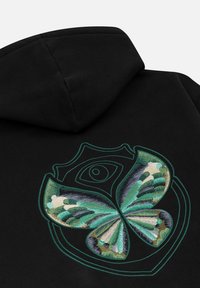 Zwarte hoodie met een geborduurde groene en blauwe vlinder binnen een schildomtrek, met daarboven een oog symbool.