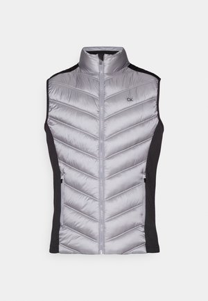 Gray puffer vest with a high collar, chevron stitching, black side panels, and front zip closure. Features a small CK logo on the chest.