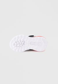 Sola de sapato preta com parte inferior branca texturizada apresentando padrões circulares e um destaque vermelho no calcanhar. Logo da marca presente.