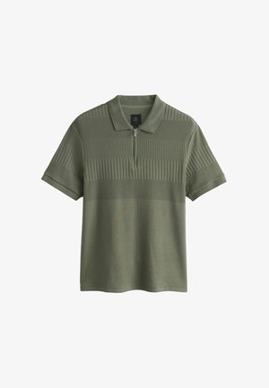 Tricou polo verde măsliniu cu mâneci scurte, guler cu fermoar și dungi orizontale texturate pe piept și partea superioară a corpului.