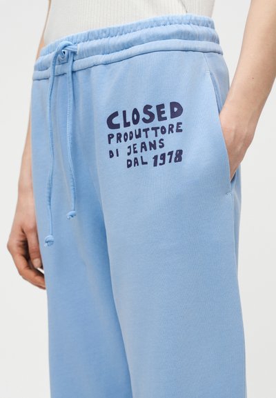 Ανοιχτό γαλάζιο φόρμας παντελόνι με ελαστική μέση και κορδόνι, με μαύρο κείμενο «CLOSED PRODUTTORE DI JEANS DAL 1978» στο αριστερό ισχίο.