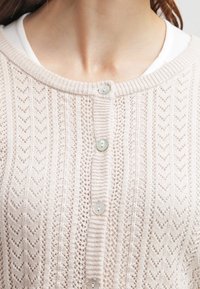 Lichtbeige gebreide cardigan met een zigzagpatroon, met een ronde halslijn, zes knopen en een gestructureerde stof.