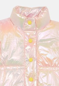 Giacca imbottita in materiale rosa iridescente, con un colletto alto e cinque bottoni a pressione gialli sul fronte. Superficie testurizzata con design trapuntato.